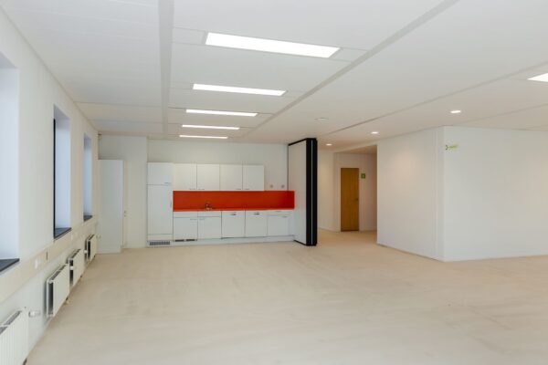 Moderne, lege kantoorruimte aan de Boris Pasternaklaan met een witte kitchenette en feloranje achterwand.